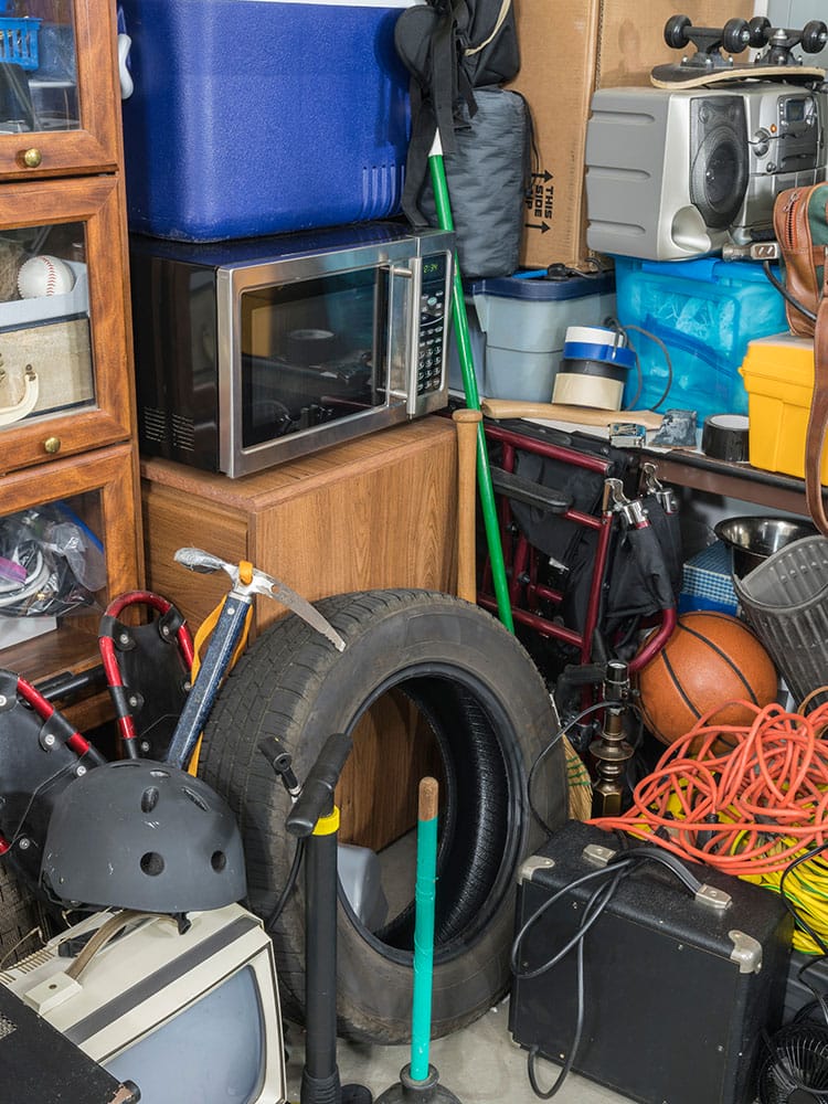 A cluttered room with many items and a microwave.