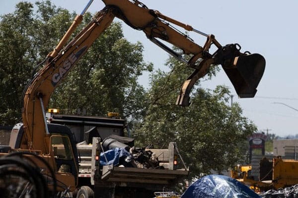 A large crane is lifting rubble from the back of a dump truck.